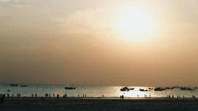 夕阳下海滩上的人群与渔船